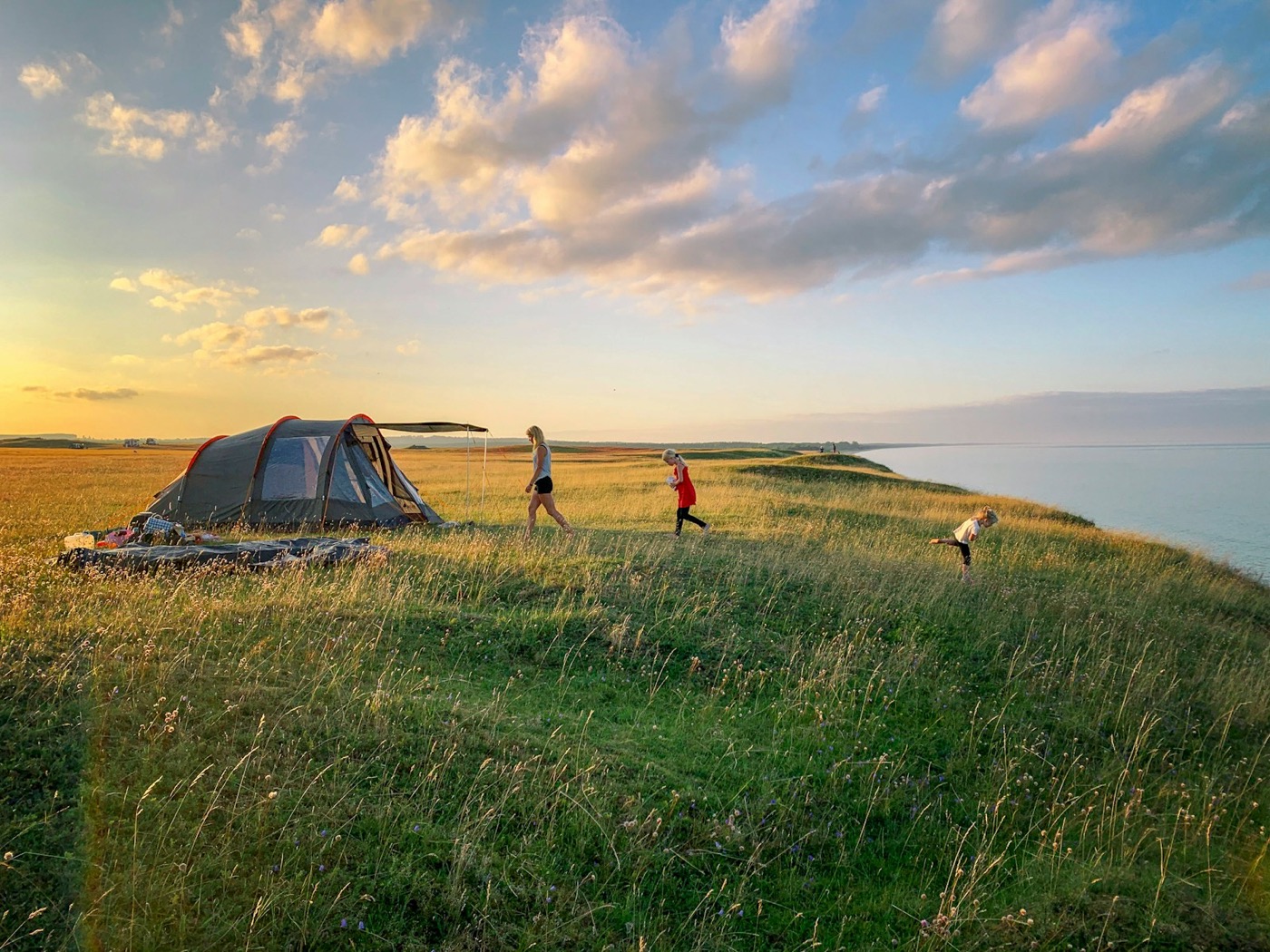 A family pitching their tent at sunset